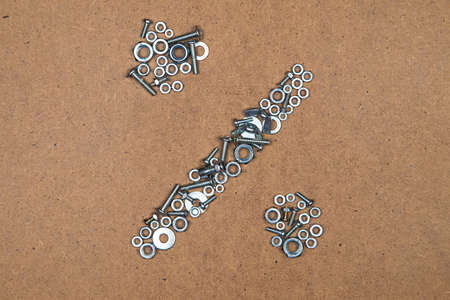 Percent from bolts and nuts. Photo of mozaic sign on wood background.