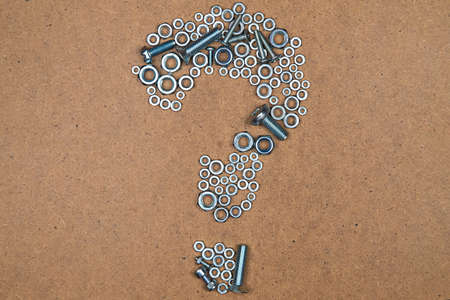 Question from bolts and nuts. Photo of mozaic sign on wood background.の写真素材