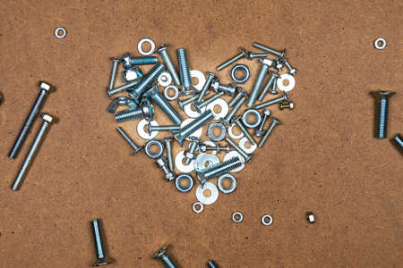 Bright heart from bolts and nuts. Photo of mozaic sign on wood background.の写真素材