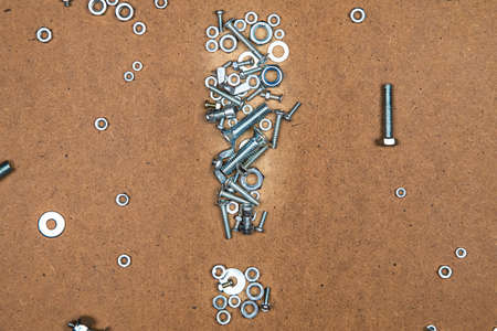Bright exclamation mark from bolts and nuts. Photo of mozaic sign on wood background.