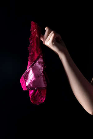 Hand and panties on black background. Photo of woman's body in shadow.の写真素材