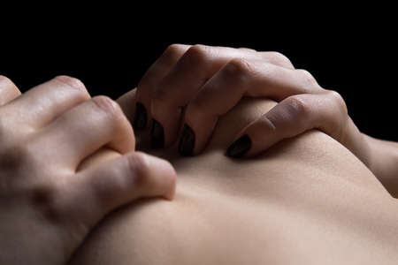 Woman's hands holding big breasts close up. Photo of a woman in shadow.の写真素材