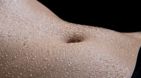 Woman's belly with drops in the dark. Photo of a woman in shadow.の写真素材