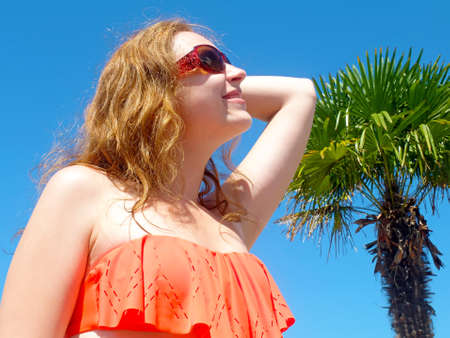 Happy blond woman looking up, in the summer