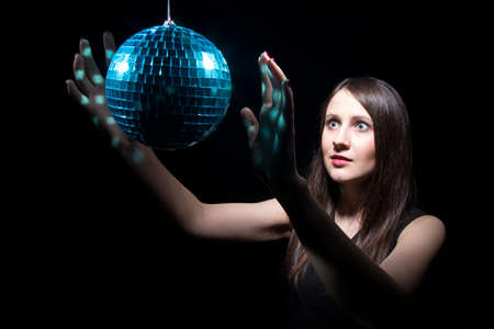 Young woman with disco ball on black background