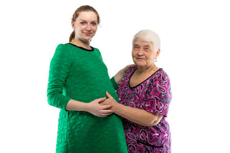 Smiling grandma touching belly of pregnant granddaughter, family on white background