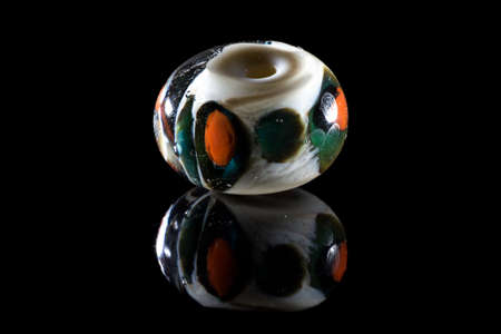 Transparent white and green glass bead with reflection on black backgroundの写真素材