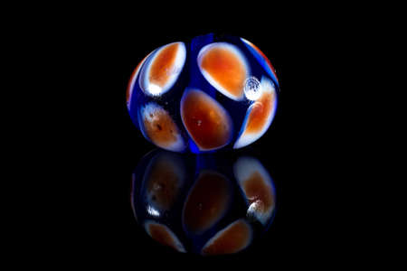 Orange and blue glass bead with reflection on black backgroundの写真素材