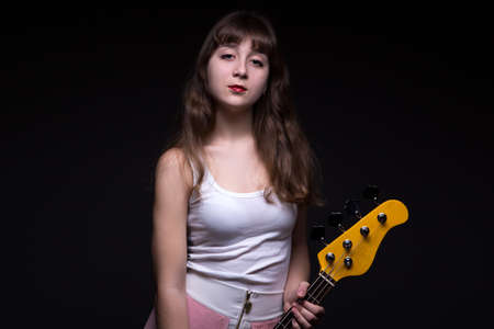 Arrogant teenage girl in shadow with guitar on black backgroundの写真素材