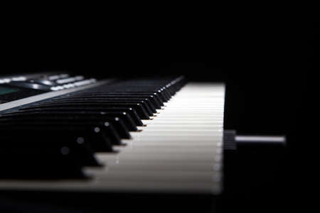 Piano keys in shadow on black backgroundの写真素材
