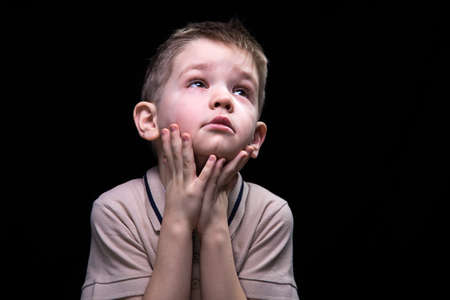 Little boy looking up, close up on black backgroundの写真素材