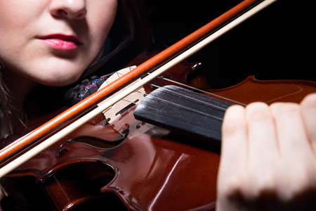 Woman playing on violin, close up on black backgroundの写真素材