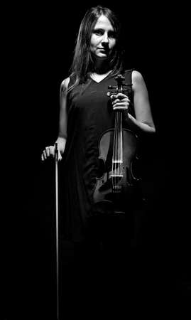 Black and white photo of woman with violin on black backgroundの写真素材