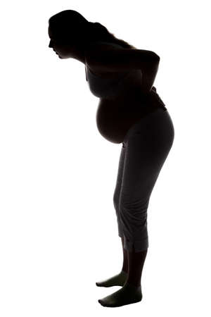 Silhouette of pregnant woman with low back pain on white backgroundの写真素材