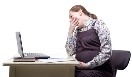 Yawning expectant mother in office on white backgroundの写真素材