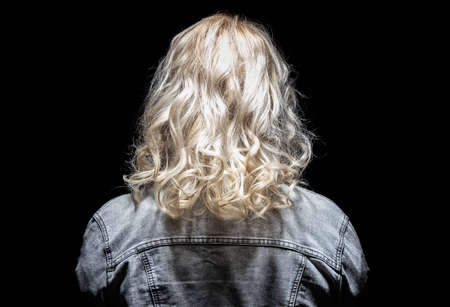 Woman's back and jeans jacket on black backgroundの写真素材