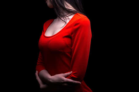 Woman with arms crossed in red dress on black backgroundの写真素材