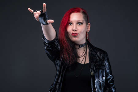 Informal woman with devil horns gesture on gray backgroundの写真素材