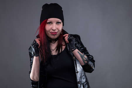 Punk woman in leather jacket with headdress on gray background