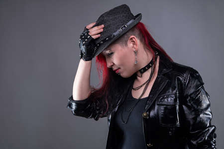 Welcoming punk woman in black hat on gray backgroundの写真素材