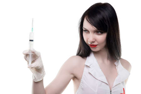 Brunette nurse looking at syringeの写真素材