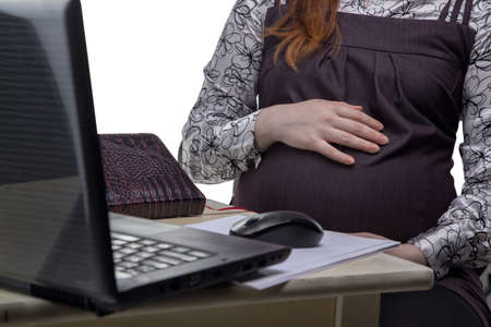 Pregnant woman hugging belly at workの写真素材