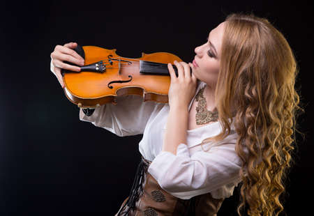 Blond young woman looking at violinの写真素材