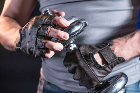 Muscular man in sporty gloves holding dumbbellの写真素材