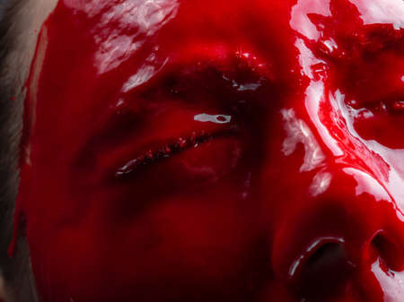 Photo of woman's face with draining red paint, close-up