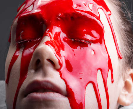 Photo of woman's face with draining red paint, close-upの写真素材