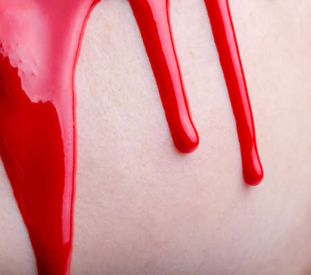 Photo of woman's face with draining red paint, close-upの写真素材