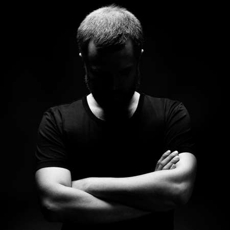 Photo of man with head down and face in shadowの写真素材
