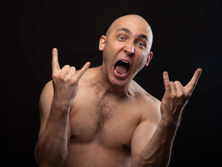 Bald man with bare shoulders and goat gestureの写真素材