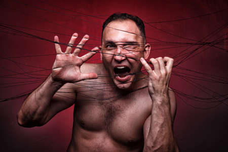 Image of tangled in black threads muscular man