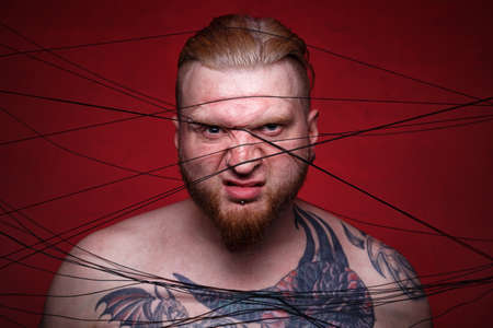 Photo of tangled in black threads bearded frowned manの写真素材