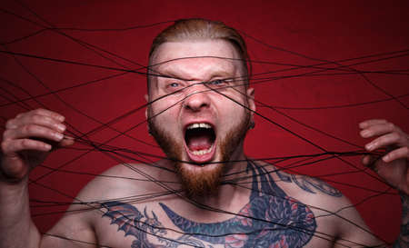 Image of tangled in black threads bearded screaming manの写真素材