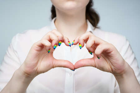 Photo of woman with rainbow manicure showing heartの写真素材