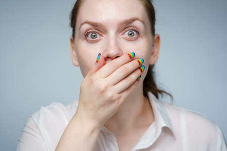 Photo of girl with rainbow manicure covering her mouth