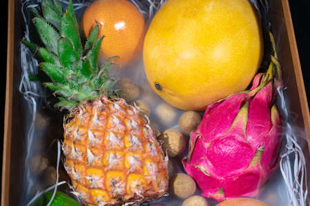 Image of wooden box with different exotic fruits in smoke