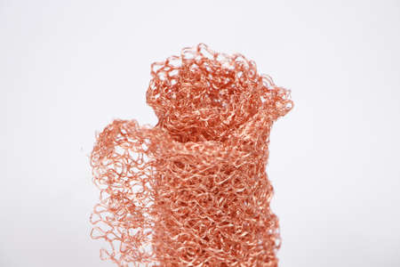 Photo of rolled red metal knitted grid on white background