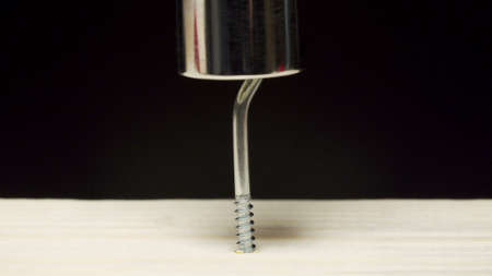 Photo of screwdriver drilling an iron screw into a wooden board