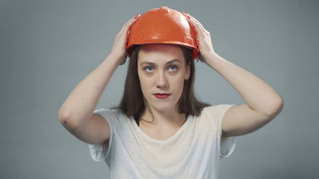 Photo of woman wearing orange helmet on greyの写真素材