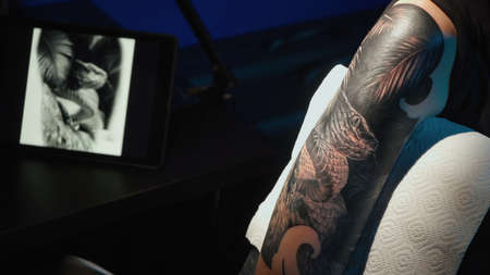 Close up photo of man doing tattoo of snake for woman in studioの写真素材