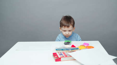Photo four year old boy sculpting in plasticine on gray backgroundの写真素材