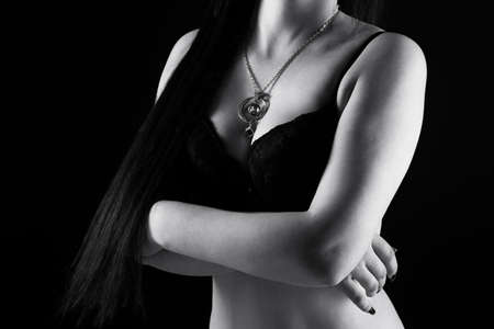 Black and white photo of brunette woman in bra with arms crossedの写真素材