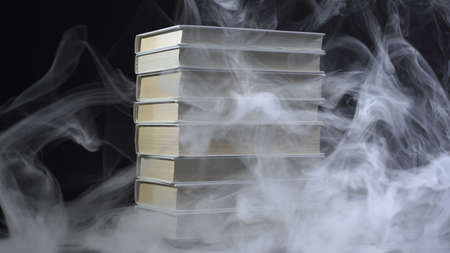 Horror photo of books among smoke on blackの写真素材