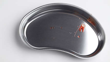 Bloodied wisdom tooth in a kidney-shaped tray