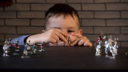 Photo of four-year-old kid playing with tin soldiers
