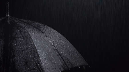 Black umbrella and rainy drops on black background