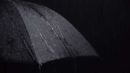 Photo of black umbrella and raindrops on black backgroundの写真素材